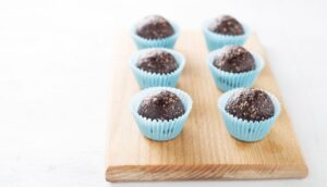 Homemade healthy gluten-free no bake brownie energy bites on cutting board on the white table.